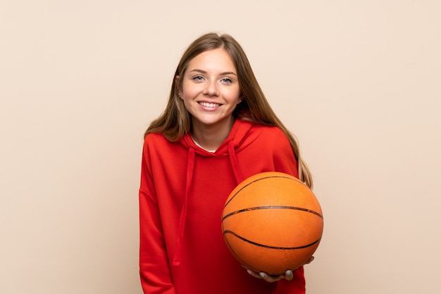 Junge blonde Frau über getrennter Wand mit Kugel des Basketballs