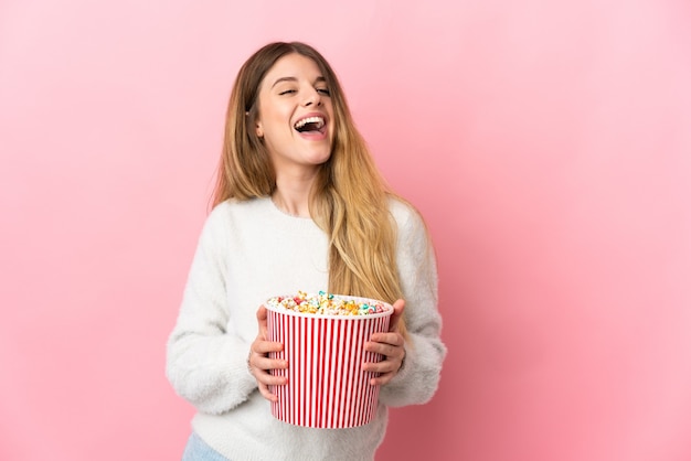 Junge blonde Frau über isoliert hält einen großen Eimer Popcorn