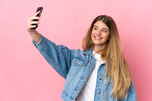 Junge blonde Frau über isoliertem Raum, der ein selfie mit Handy macht