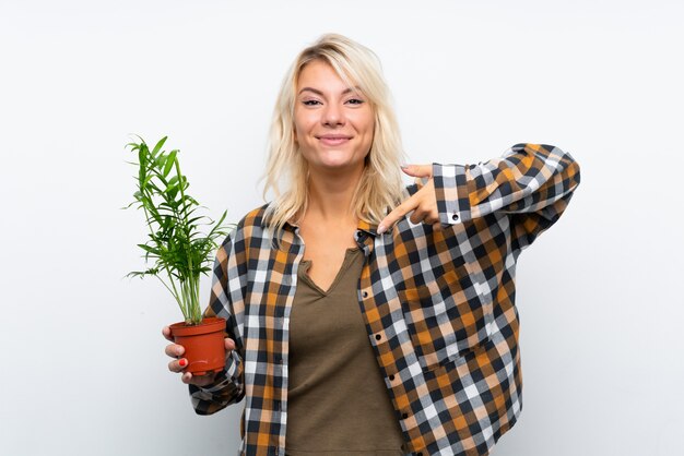 Foto junge blonde gärtnerfrau, die eine anlage hält und sie zeigt