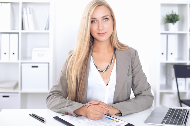 Junge blonde Geschäftsfrau mit Laptop im Büro.