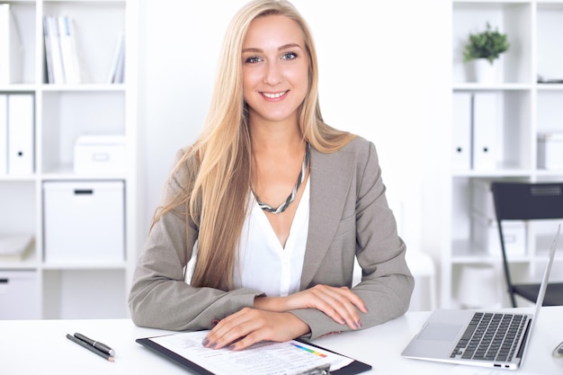 Junge blonde Geschäftsfrau mit Laptop im Büro.