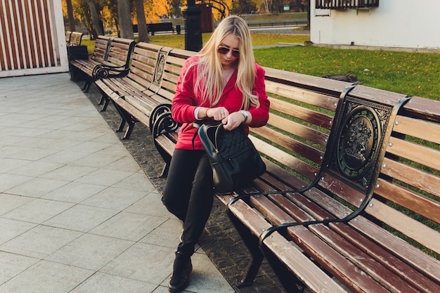 Junge blonde Geschäftsfrau mit Tasche im Park.