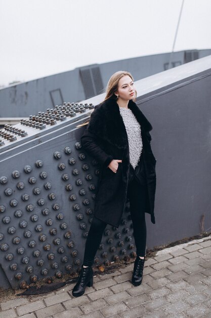 Junge blonde Geschäftsfrau nahe Brücke. Wandern entlang der europäischen Stadt