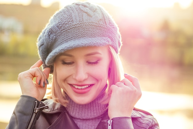 Junge blonde glücklich lächelnde naive Blickfrau in französischem blauem Barettmantel und warmem Hut im Freiennahaufnahmeporträt perfektes Haut- und Tagesmake-up im Herbstpark. Kalt draußen. Winter-Frühlingskleidung