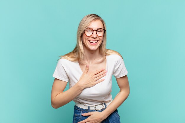 Junge blonde hübsche Frau, die laut über einen urkomischen Witz lacht, sich glücklich und fröhlich fühlt und Spaß hat