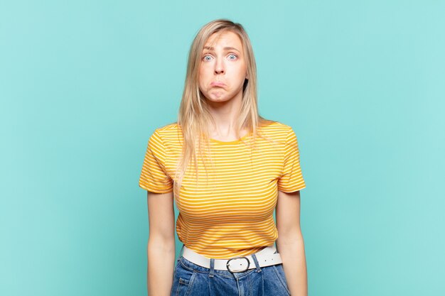Junge blonde hübsche Frau, die traurig und gestresst ist, verärgert wegen einer bösen Überraschung, mit einem negativen, ängstlichen Blick