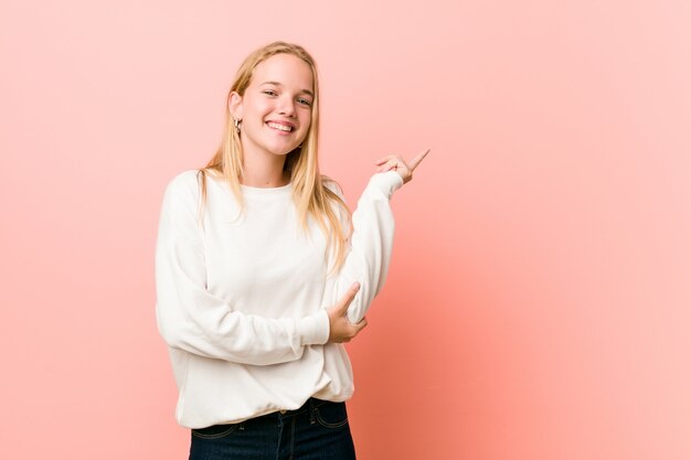 Junge blonde Jugendlichfrau, die mit dem Zeigefinger weg freundlich zeigen lächelt.