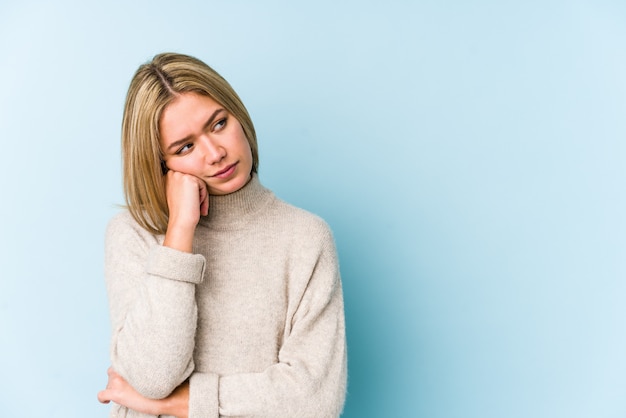 Junge blonde kaukasische Frau, die sich traurig und nachdenklich fühlt und Leerzeichen betrachtet.