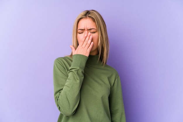 Junge blonde kaukasische Frau isolierte Gähnen, das eine müde Geste zeigt, die Mund mit Hand bedeckt.