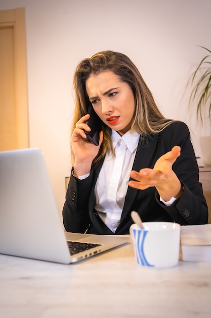 Junge blonde kaukasische Frau mit einem Kaffee, der mit dem Computer arbeitet