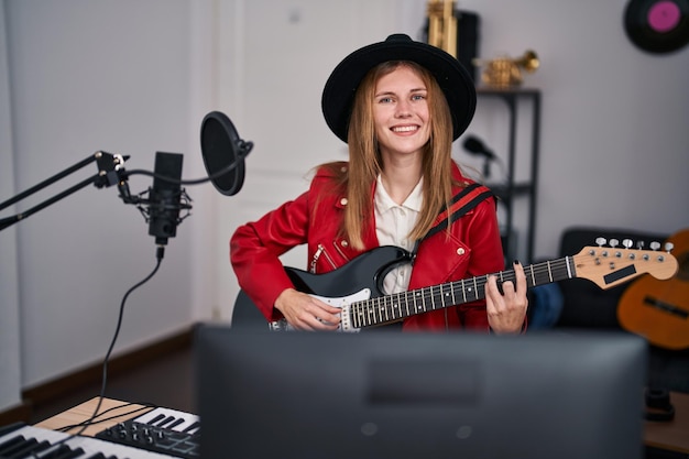 Junge blonde Musikerin singt ein Lied und spielt E-Gitarre im Musikstudio