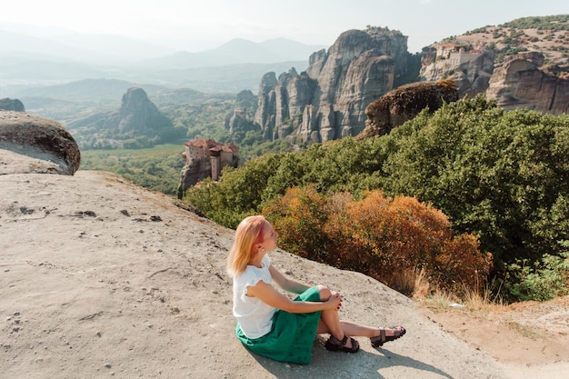 Junge blonde positiv lächelnde Frau Reisende steht hoch in den Bergen Klöster meteora Griechenland
