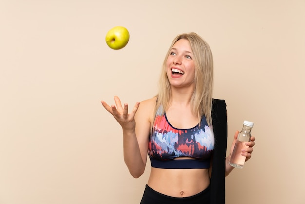 Junge blonde Sportfrau mit einem Apfel und einer Flasche Wasser