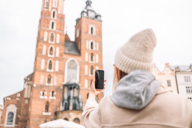 Junge blonde Touristin macht ein Selfie mit dem Handy auf dem Marktplatz in Krakau in Polen