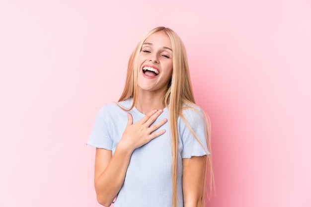 Junge Blondine auf rosa Wand lachen laut, Hand auf Kasten halten.