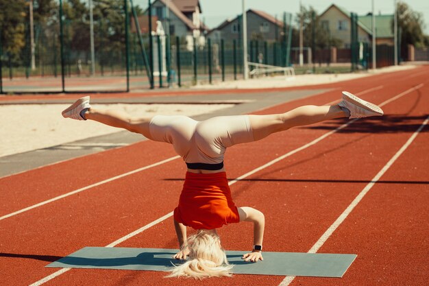 Junge Blondine lernt im Kopfstand und Handstand zu balancieren