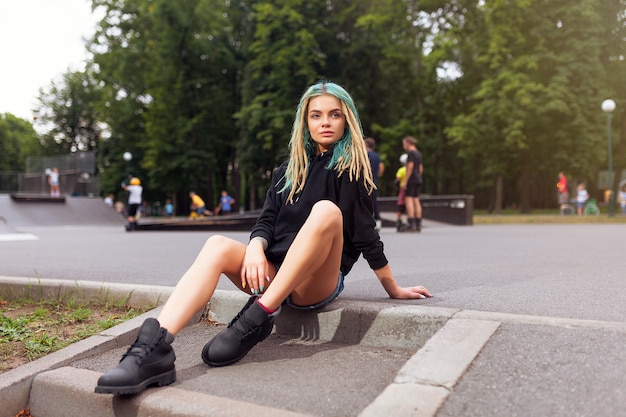 Junge Blondine mit Dreadlocks sitzen auf dem Rochenpark