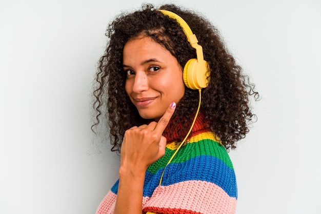 Junge Brasilianerin, die Musik isoliert auf blauem Hintergrund hört