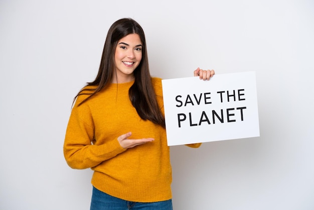 Junge Brasilianerin isoliert auf weißem Hintergrund, die ein Plakat mit dem Text Save the Planet hält und darauf zeigt