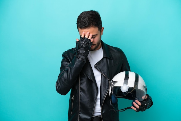 Junge Brasilianerin mit Motorradhelm isoliert auf blauem Hintergrund mit müdem und krankem Ausdruck