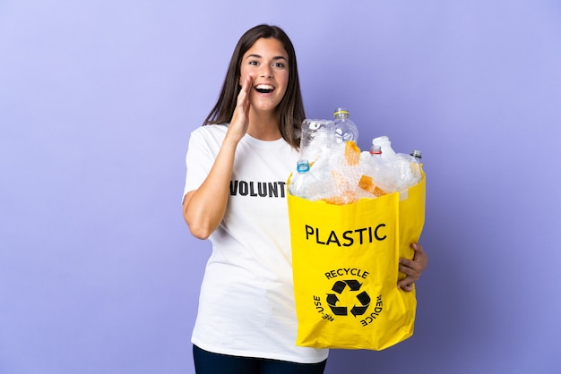 Junge brasilianische Frau, die eine Tasche voller Plastikflaschen hält, um isoliert zu recyceln