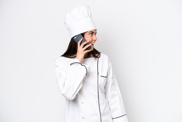 Junge brasilianische Köchin isoliert auf weißem Hintergrund, die mit jemandem ein Gespräch mit dem Handy führt