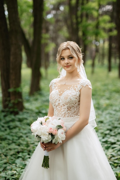 junge Braut in einem weißen Kleid in einem Frühlingswald