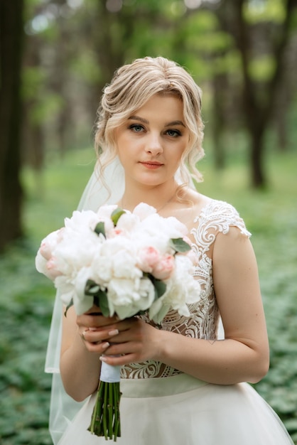 junge Braut in einem weißen Kleid in einem Frühlingswald