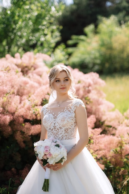 junge Braut in einem weißen Kleid in einem Frühlingswald