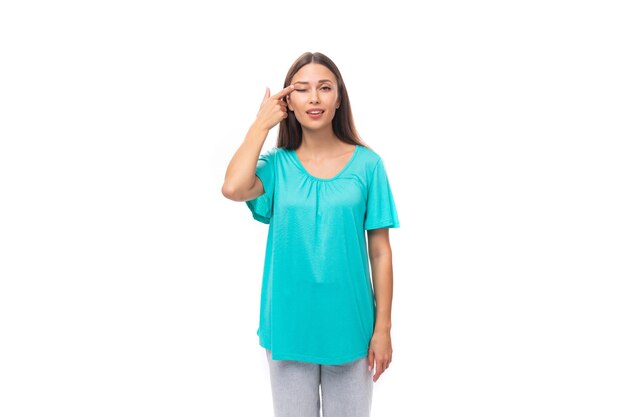 Junge brünette europäische Dame mit geraden Haaren, gekleidet in einem blauen T-Shirt, bedeckte ihr Auge mit ihrem