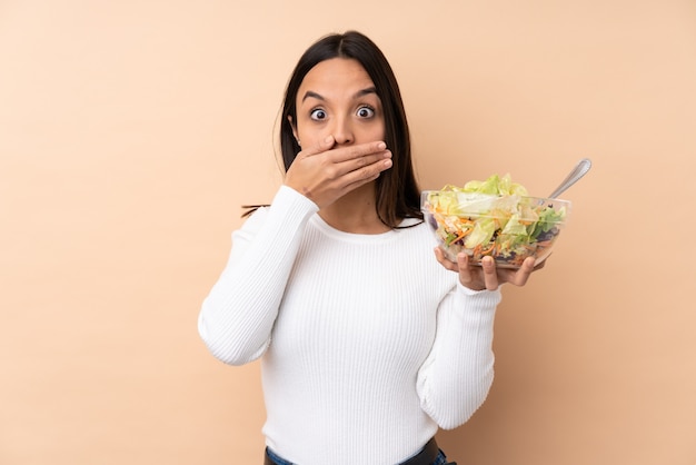 Junge brünette Frau, die einen Salat hält Mund mit Händen bedeckt