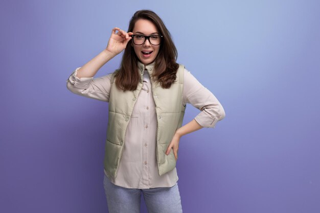 Junge brünette Frau hält eine Brille in den Händen auf einem Studiohintergrund mit Kopierraum