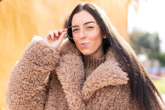 Junge brünette Frau im Freien mit Brille und frustriertem Ausdruck