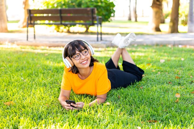 Junge brünette Frau im Freien Musik hören mit dem Handy und glücklich