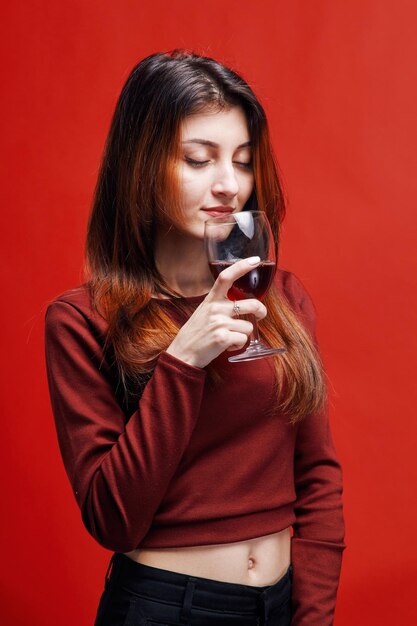 Junge brünette Frau in roter Bluse mit einem Glas Rotwein in der Hand