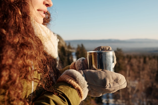 Junge brünette Frau in Winterkleidung mit Becher