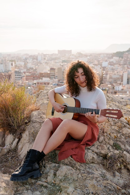 Junge brünette Frau lernt im Freien klassische Gitarre zu spielen