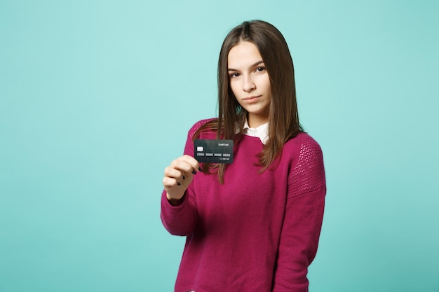 Junge brünette Frau Mädchen in Freizeitkleidung posiert isoliert auf blauem türkisfarbenem Hintergrund Studioportrait. Menschen aufrichtige Emotionen Lifestyle-Konzept. Mock-up-Kopienbereich. Halten Sie die Kreditkarte in der Hand.