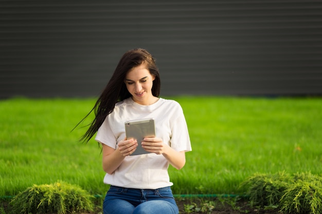 Foto junge brünette frau mit tablette leibeigenschaft im internet auf gras