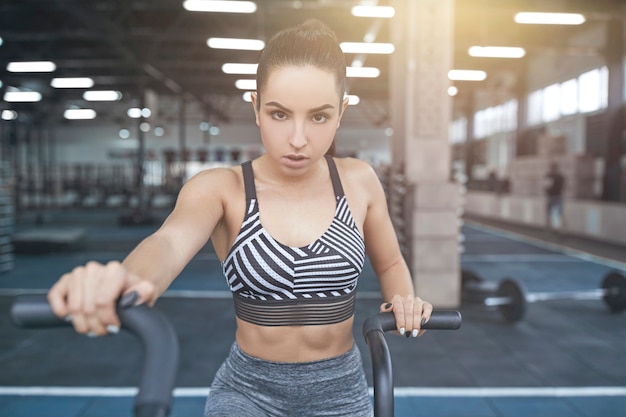 Junge brünette Frau trainiert im Fitnessstudio mit Hantel auf den Schultern