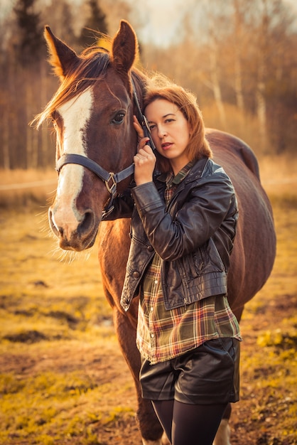 Junge brünette Frau und Pferd auf Herbstnatur