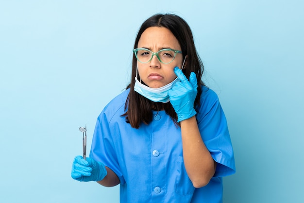 Junge Brünette gemischte Rasse Zahnarzt Frau, die Werkzeuge über etwas zeigt