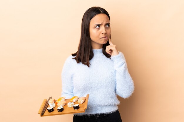 Junge brünette Mischrassenfrau, die Sushi isoliert hält