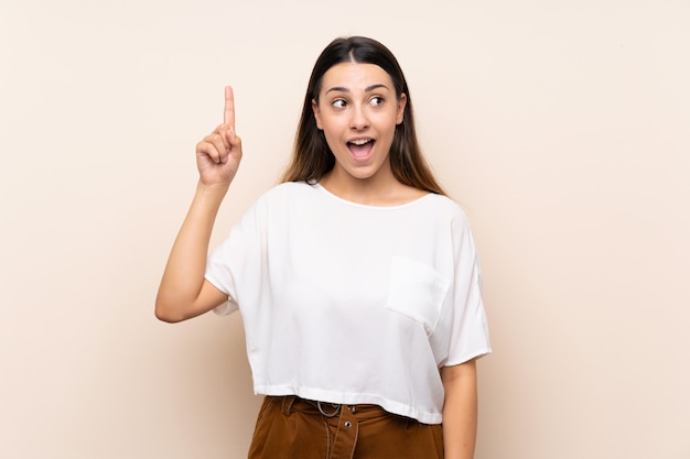 Junge Brunettefrau, die beabsichtigt, die Lösung beim Anheben eines Fingers zu verwirklichen