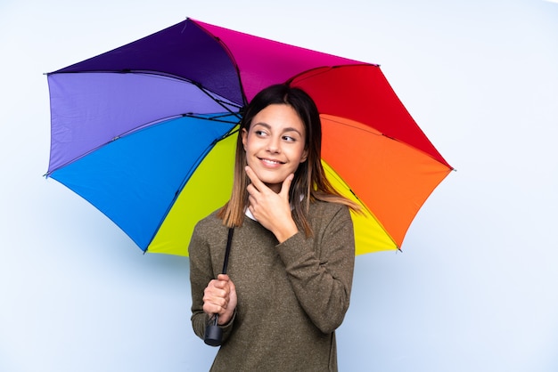 Junge Brunettefrau, die einen Regenschirm denkt eine Idee hält