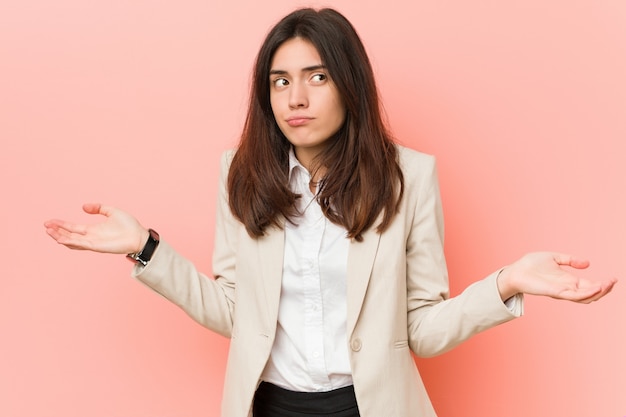 Junge Brunettefrau, die Schultern in fragender Geste zweifelt und zuckt.