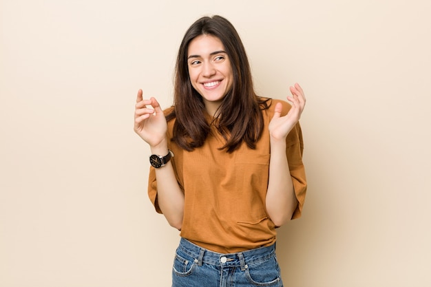 Junge Brunettefrau gegen einen beige Hintergrund froh, viel lachend