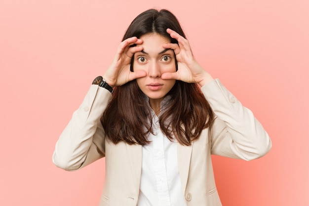 Junge BrunetteGeschäftsfrau gegen eine rosa Wand, die Augen hält, öffnete sich, um eine Erfolgschance zu finden.