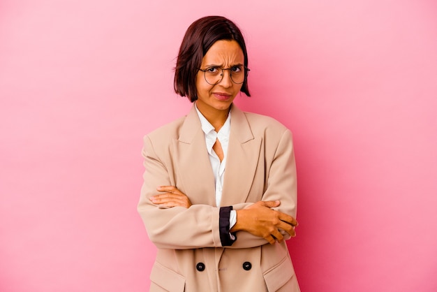 Junge Business-Mixed-Race-Frau isoliert auf rosa Hintergrund misstrauisch, unsicher, untersucht Sie.